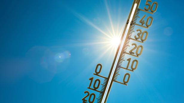 Ein Thermometer wird in den blauen Himmel gehalten.