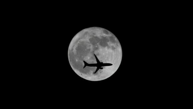 FILE PHOTO: Passenger plane passes the moon as it comes into land at the international airport in Chennai
