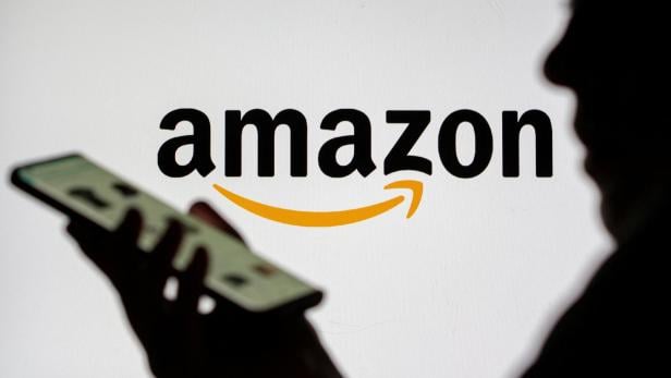 FILE PHOTO: Woman with smartphone is seen in front of displayed Amazon logo in this illustration taken