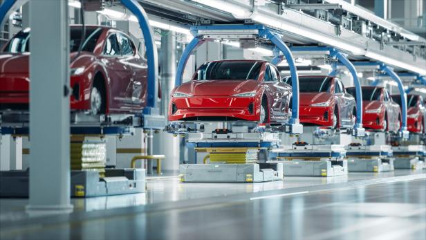Eine Reihe roter Autos auf einer Produktionslinie in einer Fabrik.