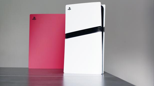Eine weiße PlayStation 5 Konsole steht neben einer pinkfarbenen Abdeckung.