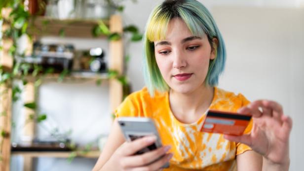 Symbolbild: Eine Frau mit Kreditkarte und Smartphone.