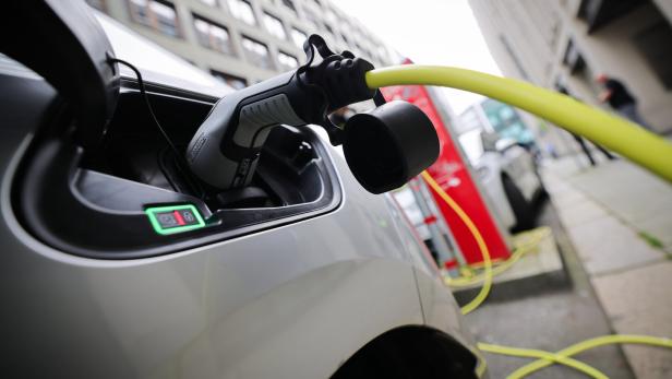 Ein Elektroauto wird an einer Ladestation mit einem gelben Kabel aufgeladen.