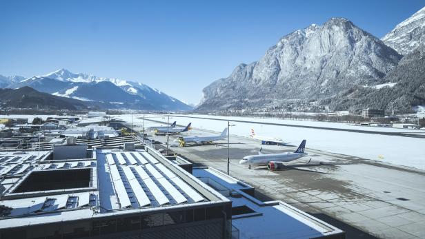 Der Flughafen Innsbruck im Winter mit schneebedeckten Bergen im Hintergrund.
