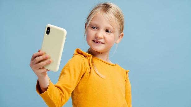 Ein blondes Mädchen macht ein Selfie mit ihrem Handy.