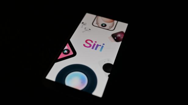 Das Siri-Logo auf einem hell erleuchteten Smartphone-Display in dunkler Umgebung.