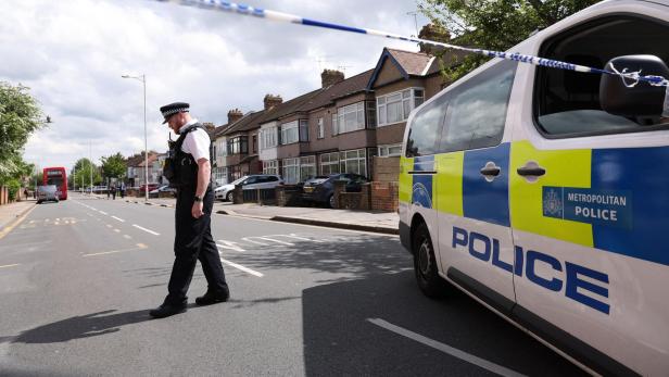 Britische Behörden wollen mit einem „Mord-Vorhersage-Programm“ die öffentliche Sicherheit erhöhen. Bürgerrechtsorganisationen schlagen Alarm (Symbolbild). Ein britischer Polizist neben einem Polizeiauto, an dem ein Absperrband befestigt ist
