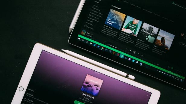 Auf zwei Tablets sind Spotify-Playlists zu sehen.