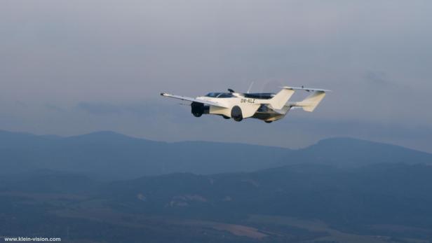 Das AirCar in der Luft, im Hintergrund eine Bergkette.