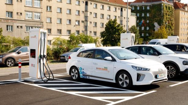 E-Autos von Wien Energie können in der österreichischen Hauptstadt bei vielen Schnellladestationen innerhalb kürzester Zeit aufgeladen werden. Ein E-Auto auf einem Parkplatz in Wien neben einer E-Ladestation von Wien Energie.