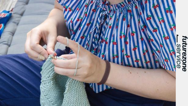 Häkeln und Stricken macht auch im Sommer Spaß (Symbolbild). eine Person in sommerlicher Bluse häkelt an einem türkisen Stück