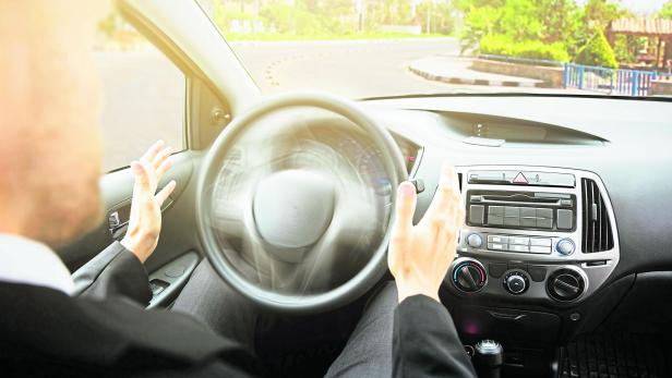 Ein Mann sitzt auf dem Fahrersitz eines selbstfahrenden Autos.