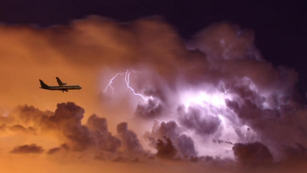 Flugzeug vor einer Gewitterwolke.