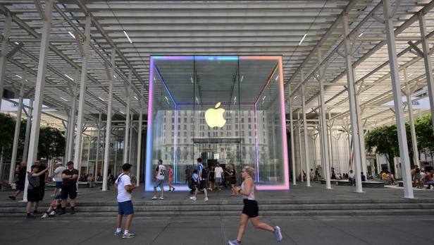 Ein Apple Store mit einem großen, leuchtenden Apple-Logo zieht Passanten an.