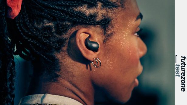 Eine Frau mit geflochtenen Zöpfen trägt einen schwarzen Sony LinkBuds Fit im Ohr.