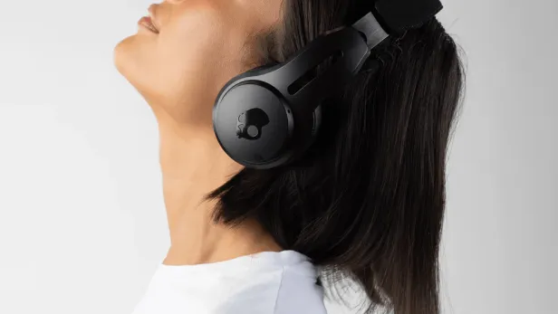 Eine Frau genießt Musik mit schwarzen Skullcandy-Kopfhörern.