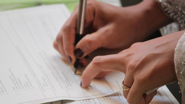 Jemand schreibt mit einem Stift auf ein Formular.