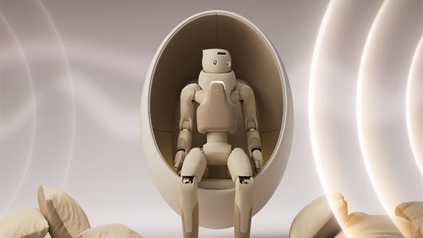 Beiger Roboter in einem beigen Sessel vor beigem Hintergrund.