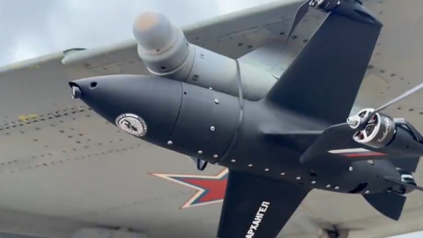 Eine Drohne ist mit Kabelbindern an einem Flugzeug befestigt.