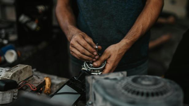 Ein Mann arbeitet mit einem Schraubenschlüssel an einem Motorrad.