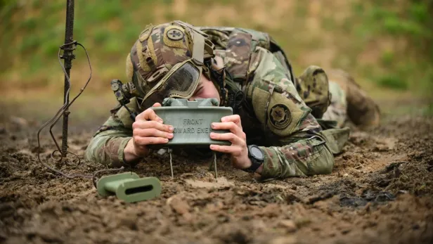 Ein Soldat stellt eine Claymore-Mine am Boden auf.