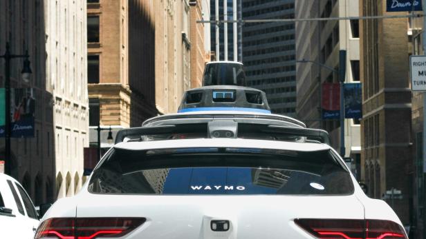 Ein weißer Waymo Jaguar fährt durch eine Stadt.