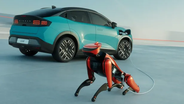 Türkises Auto im Hintergrund, im Vordergrund ist ein rot-schwarzer Roboterhund, der via Kabel am E-Auto angesteckt ist.