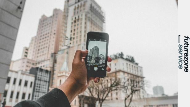 Eine Person fotografiert ein Gebäude mit einem Smartphone.