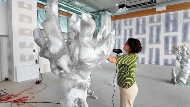Eine Frau arbeitet an einem Plastikbaum.