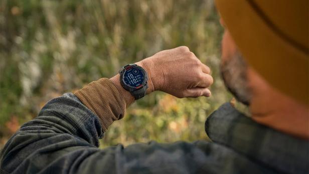 Ein Mann im Freien blickt auf seine Garmin-Smartwatch.