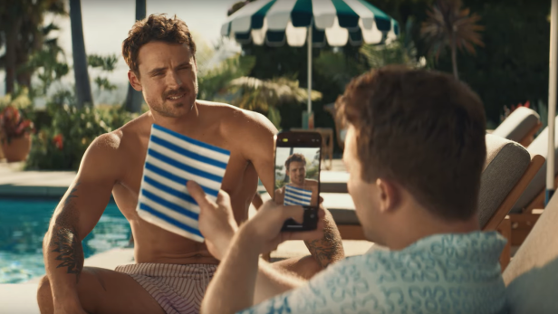 Ein Mann wird am Pool von einem anderen mit dem Handy fotografiert.