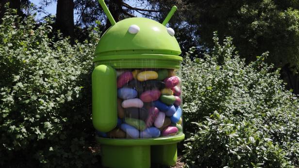 Eine grüne Android-Statue, gefüllt mit bunten Süßigkeiten, steht im Freien.