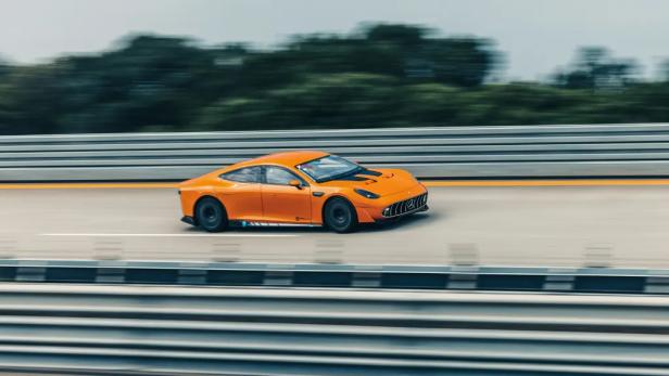 Ein orangefarbener Mercedes AMG GT XX Concept fährt auf einer Straße.