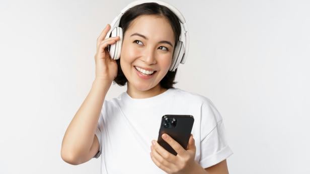 Frau mit Kopfhörern und Handy.