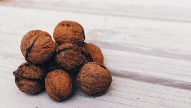 Symbolbild: Walnüsse auf Holz.