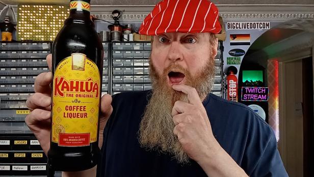 Ein Mann mit Bart und roter Mütze hält eine Flasche Kahlúa-Kaffeelikör in der Hand.