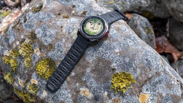 Eine Garmin Fenix 8 MicroLED Smartwatch liegt auf einem moosbedeckten Stein.