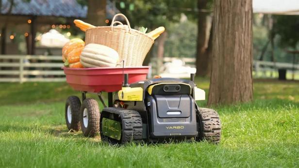 Der Gartenroboter Yarbo zieht einen Wagen mit Kürbissen und einem Korb.
