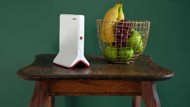 Ein Fritz!Box Router und ein Korb mit Obst stehen auf einem Tisch.