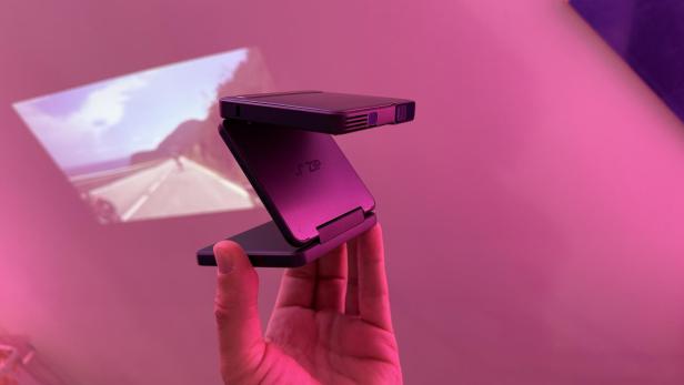 Ein Mini-Beamer der Marke Aurzen ZIP projiziert ein Bild an eine Wand.