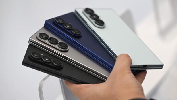 Eine Hand hält vier Samsung Galaxy Z Fold Smartphones in verschiedenen Farben.