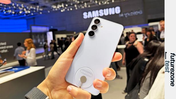 Ein hellblaues Samsung Galaxy S25 FE wird auf einer Messe präsentiert.
