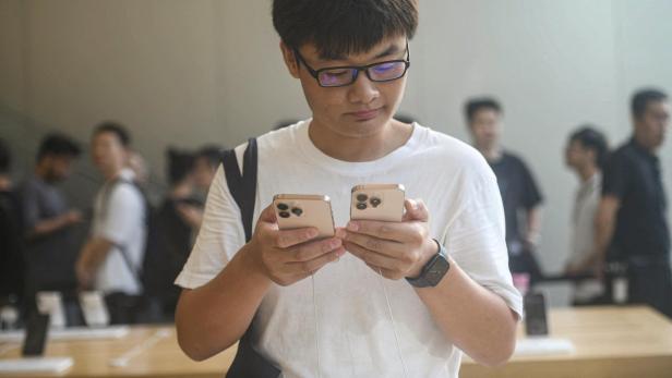Symbolbild: Mann vergleicht iPhones in China.