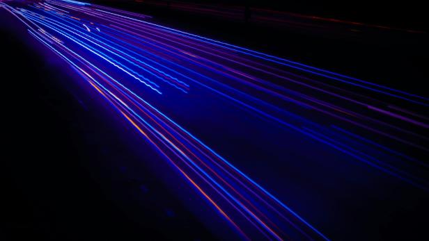 Lichtspuren von Autos auf einer dunklen Autobahn bei Nacht.