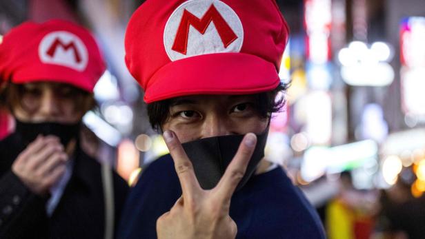 Ein Mann mit Super-Mario-Mütze zeigt ein Victory-Zeichen.