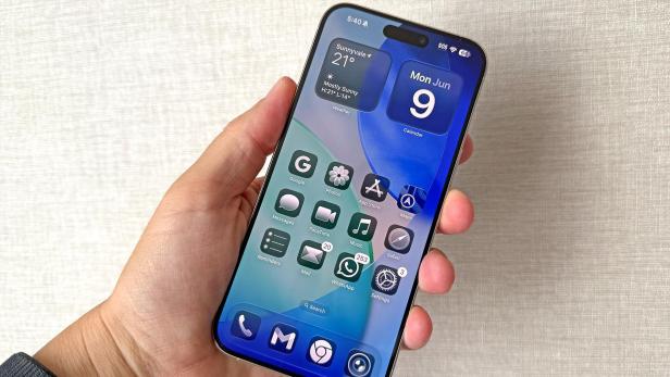 Ein iPhone zeigt iOS 26 mit Widgets und App-Symbolen.