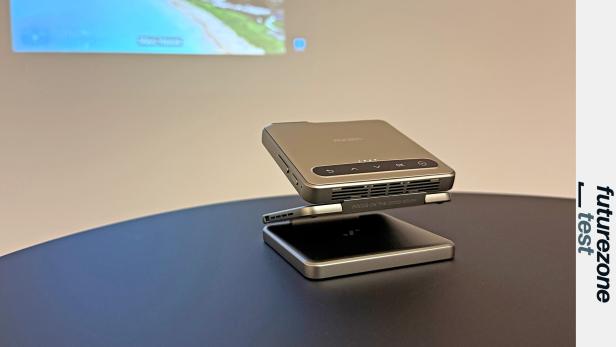 Ein Aurzen ZIP Mini-Projektor steht auf einem Tisch und projiziert ein Bild an die Wand.