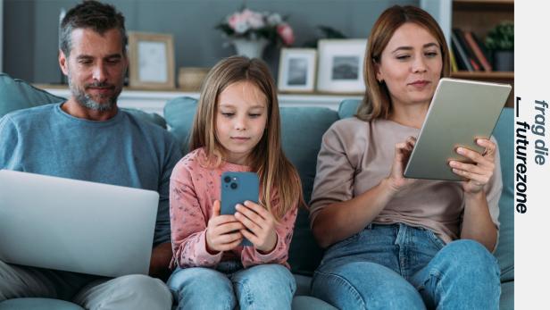 Eine Familie sitzt mit Notebook, iPhone und iPad auf der Couch.