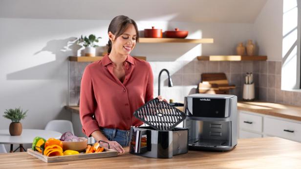 Eine Frau bereitet Gemüse für die Nutzung eines Nutribullet Airfryers vor.