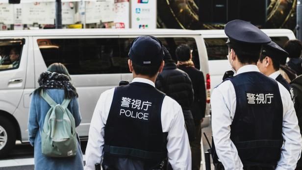Zwei japanische Polizisten blicken auf eine belebte Straße.